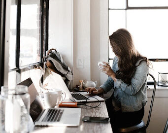 Sideview of woman with a coffee mug working at a beautifully lit coffee shop showing work-life balance Fix & Form Strategic Branding Agency Denver Colorado