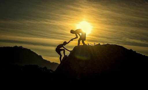 a silhouette of a person helping another person up a rock face relating to the experience of the journey and growth and how that leads to success in business Fix & Form Strategic Branding Agency Denver Colorado