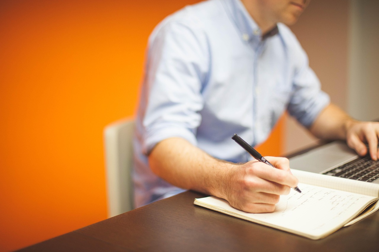 A man working at his computer writing on a notepad representing human-centered branding. Fix and Form strategic branding agency, Denver Colorado