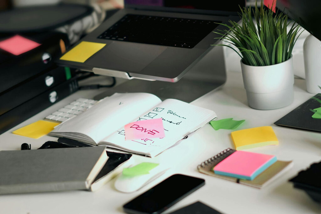 Modern workspace with notebooks, sticky notes, and a laptop showing a completed checklist, symbolizing the organization and focus behind an effective brand strategy.