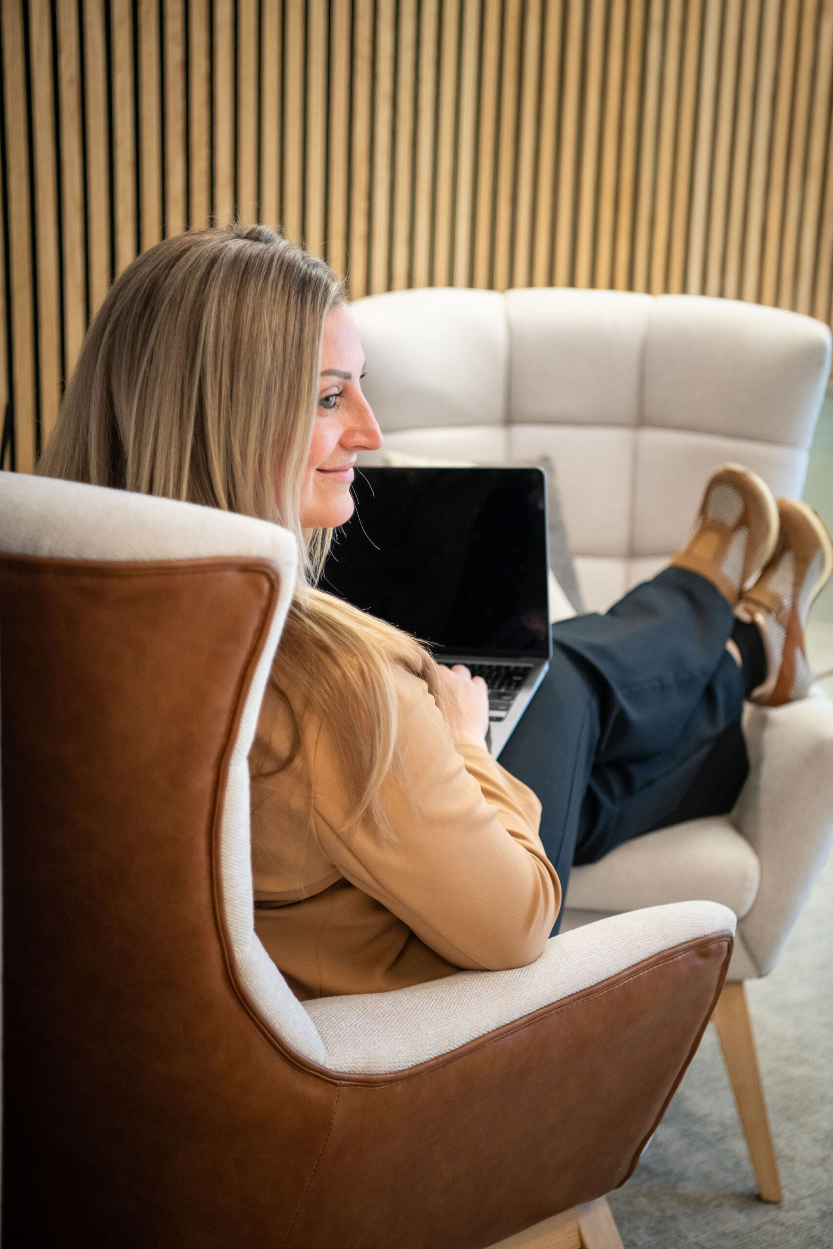 A professional woman sitting comfortably with a laptop during a brand strategy meeting, representing collaboration and trust when choosing the right branding agency.