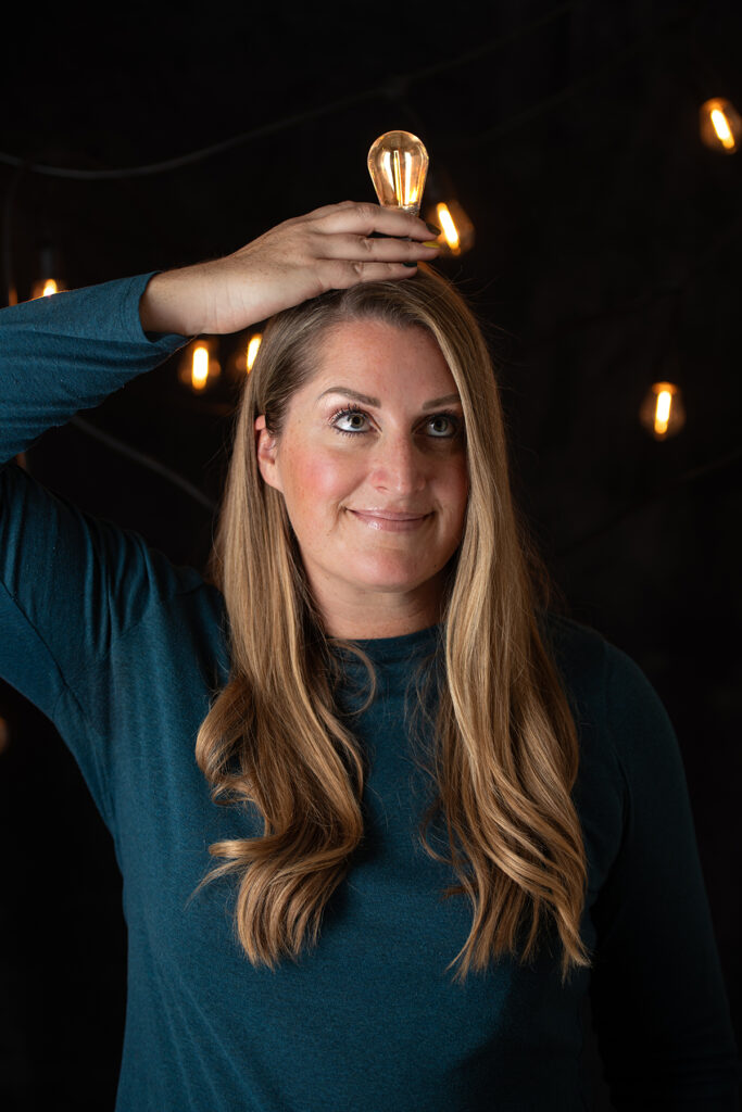 Woman holding a light bulb above her head, representing clarity, insight, and strategic brand thinking before creative execution.