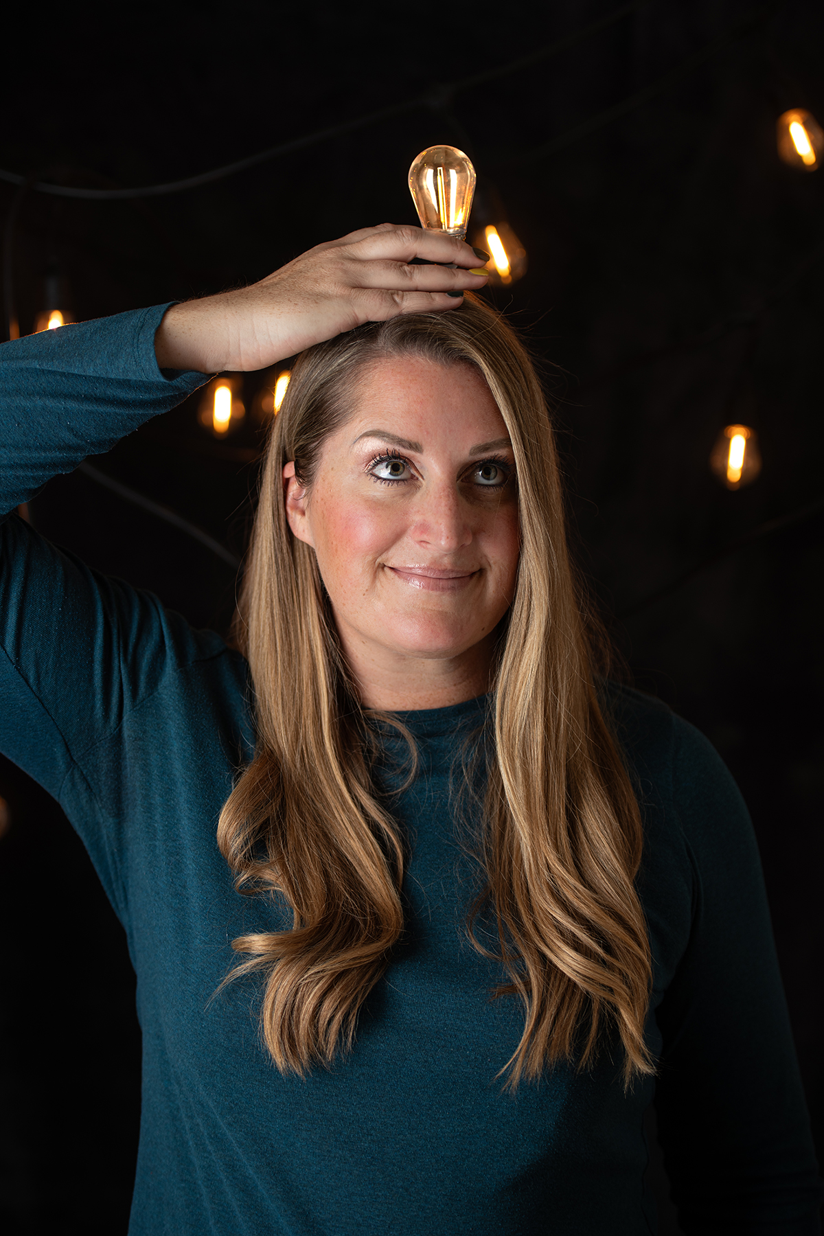 Woman holding a light bulb above her head, representing clarity, insight, and strategic brand thinking before creative execution.