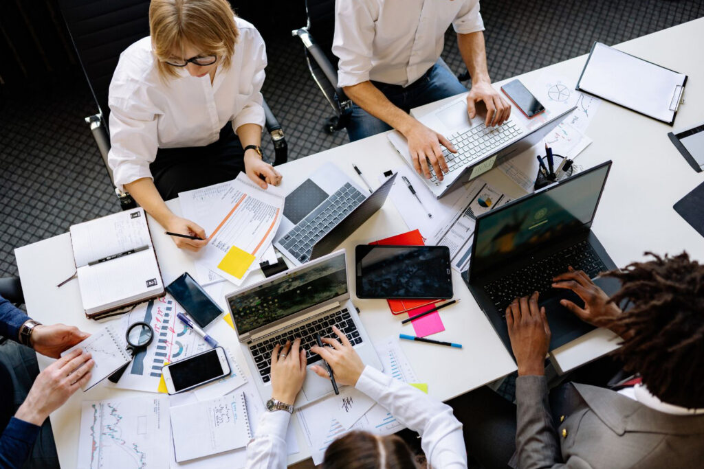 Team collaborating at a table with laptops, representing integrated work-life boundaries in modern branding