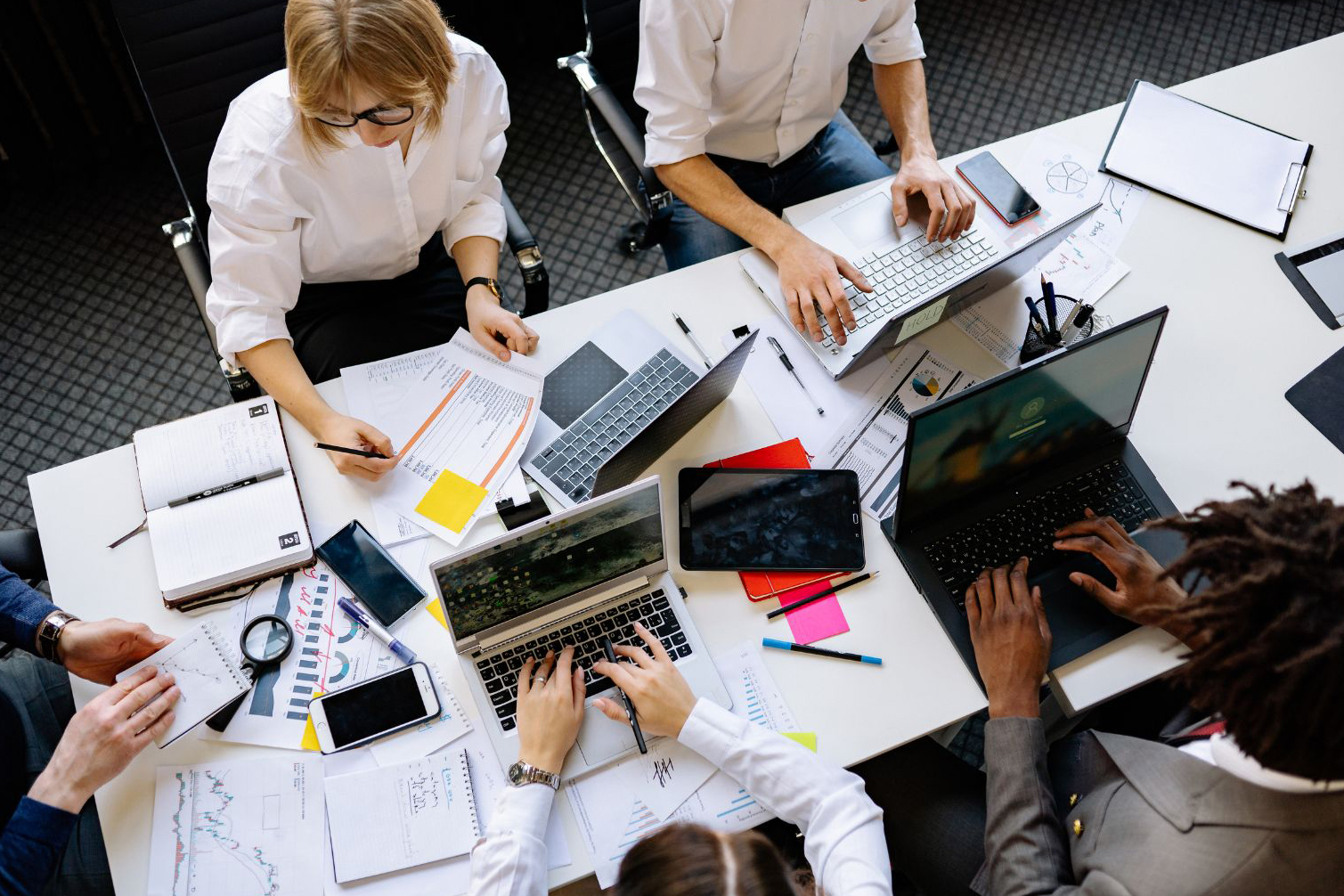 Team collaborating at a table with laptops, representing integrated work-life boundaries in modern branding