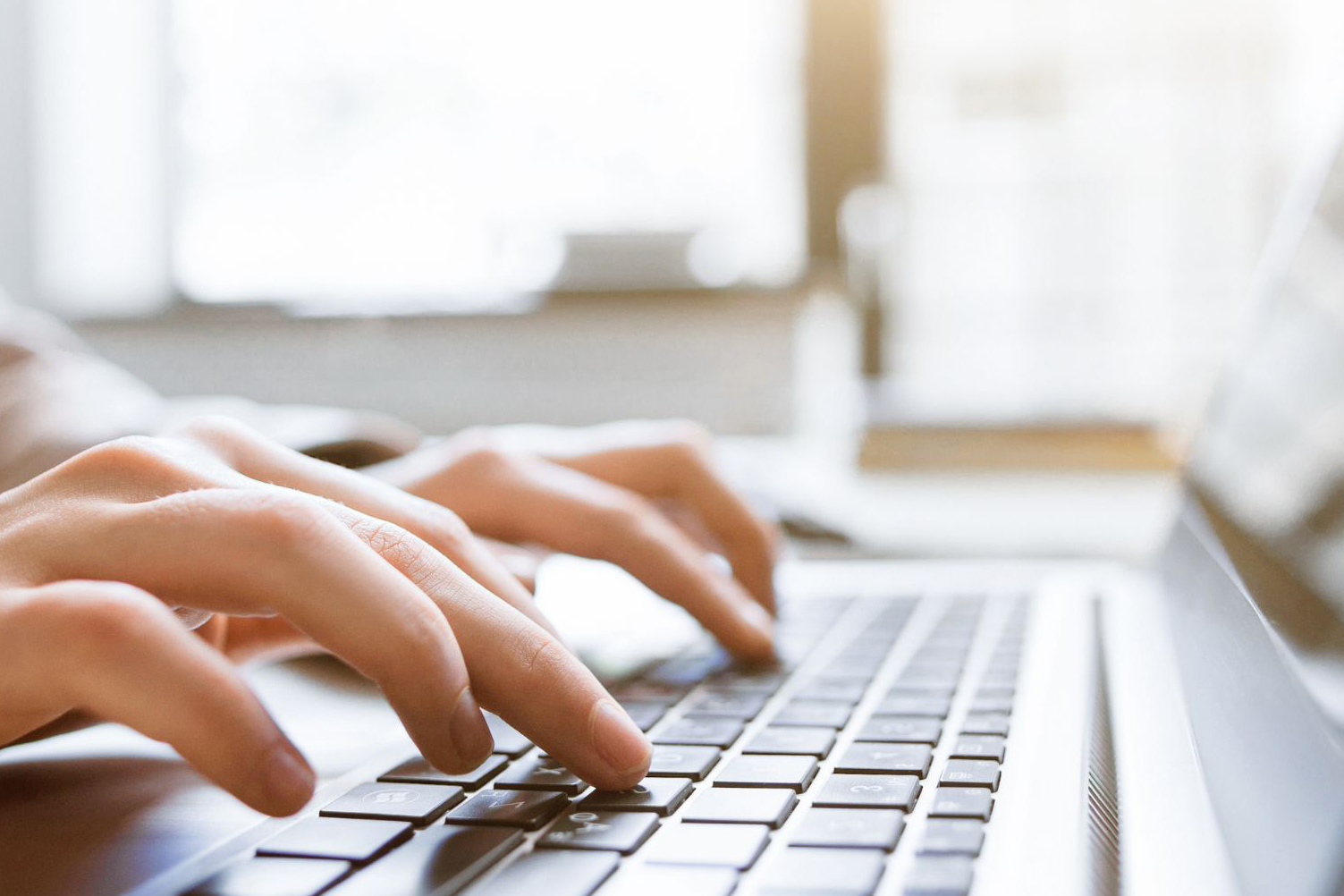 Hands typing on a laptop, representing thoughtful website strategy and brand clarity